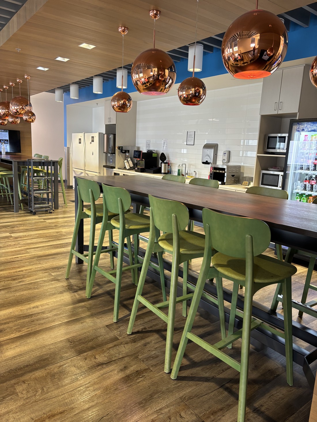 A corporate cafe area with counter seating and pendant lighting