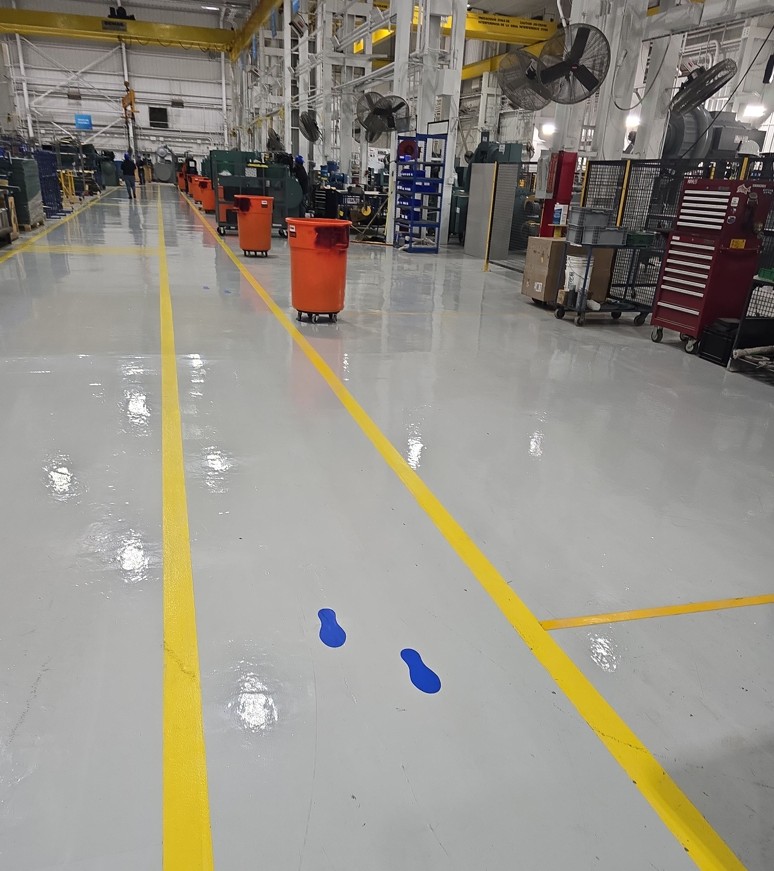 A production aisle with a gloss finish, yellow lane striping and blue standing markers