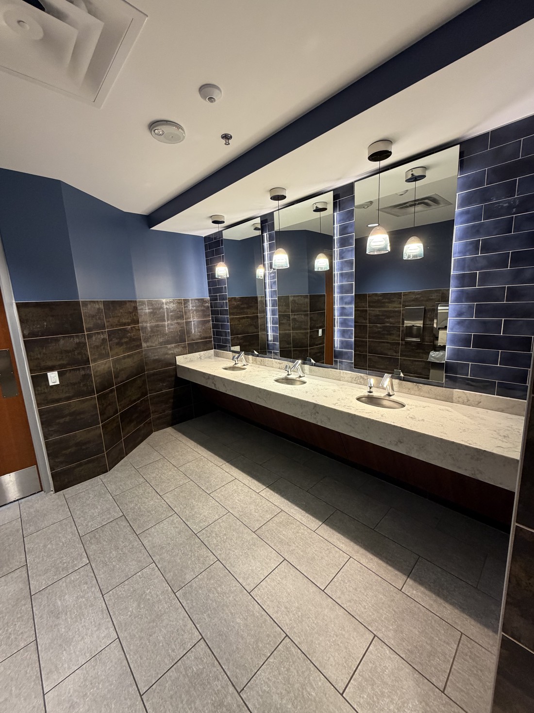 A finished restroom at an HM Solutions account with stone counters and tiled walls, cleaned and restocked