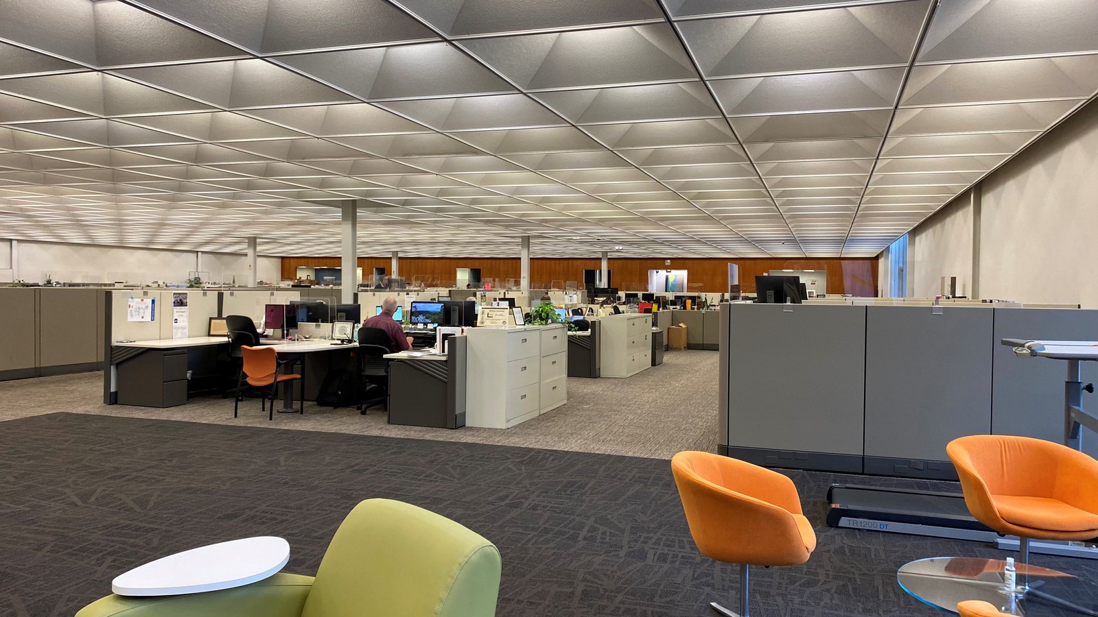 An open plan corporate office with clean carpet, workstations, and common area seating